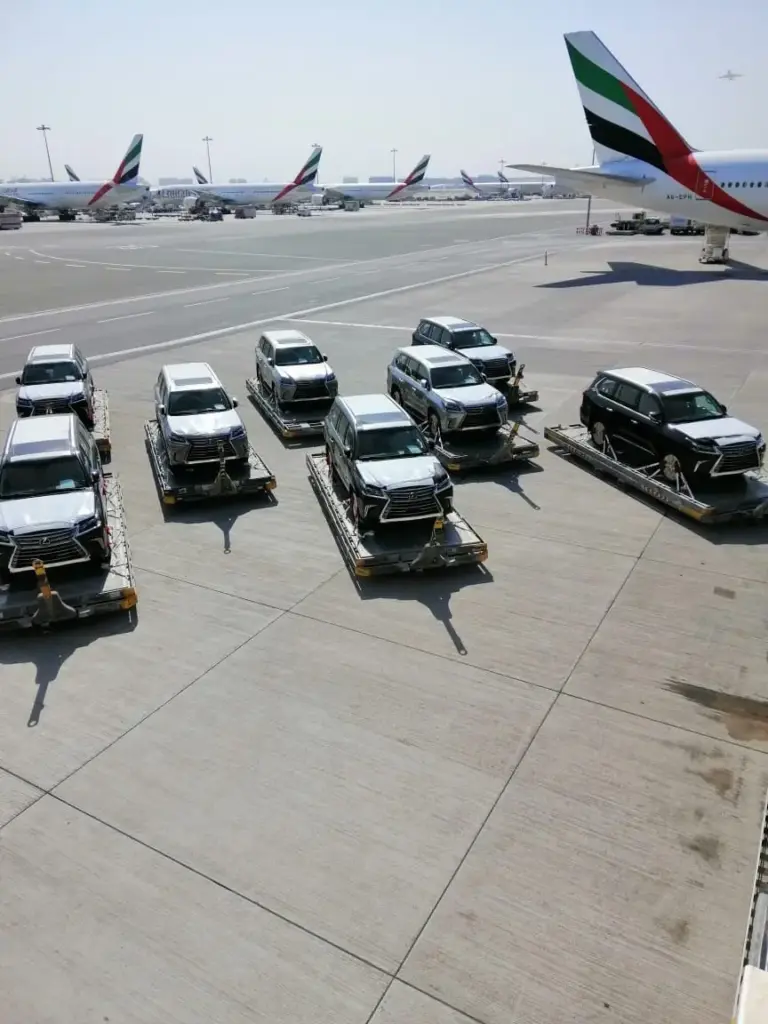 Multiple cars prepared for air freight export at an airport in UAE, representing fast and secure air car shipping services by Tawam Al Shahin Transport.